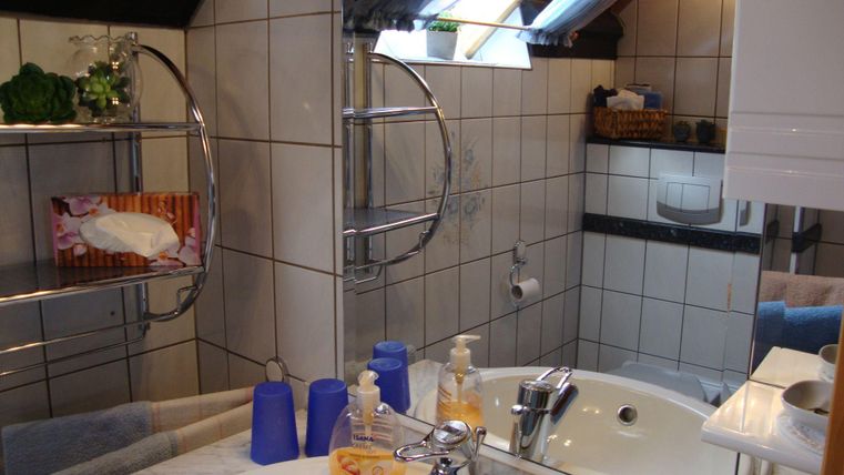 Ein modernes Badezimmer mit zwei Waschbecken und einem großen Spiegel. Die Wände sind gefliest, und es gibt verschiedene Badezimmeraccessoires.