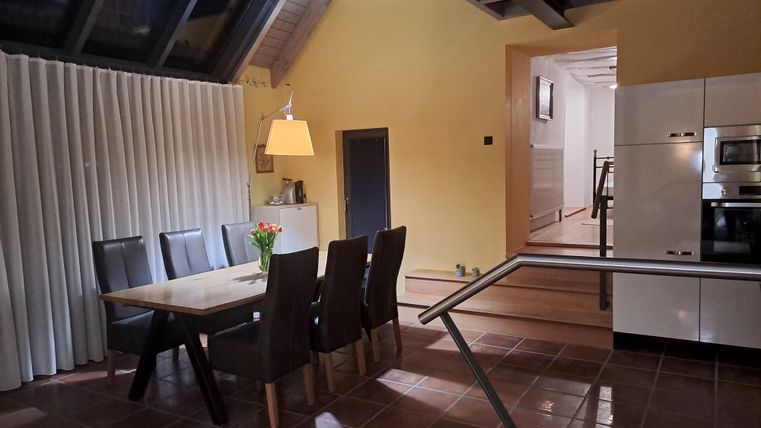 Ein modernes Esszimmer mit einem großen Tisch und sechs Stühlen. Die Wände sind in einem warmen Gelbton gehalten, und es gibt Fenster mit viel natürlichem Licht.