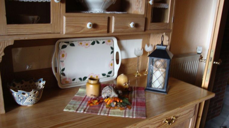 Ein schöner Holztisch mit einer dekorativen Tischdecke und verschiedenen Gegenständen. Darunter befinden sich eine Laterne, Vorratsgefäße und eine dekorative Schale.