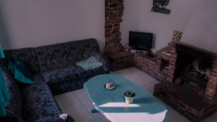 Ein gemütliches Wohnzimmer mit einer dunklen Couch und einem blauen Tisch. Im Raum befindet sich ein Kamin und ein Fernseher.