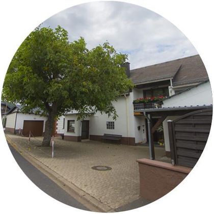 Ein schönes Haus mit einem großen Baum im Vordergrund. Der gepflasterte Platz bietet ausreichend Platz zum Sitzen und Entspannen.