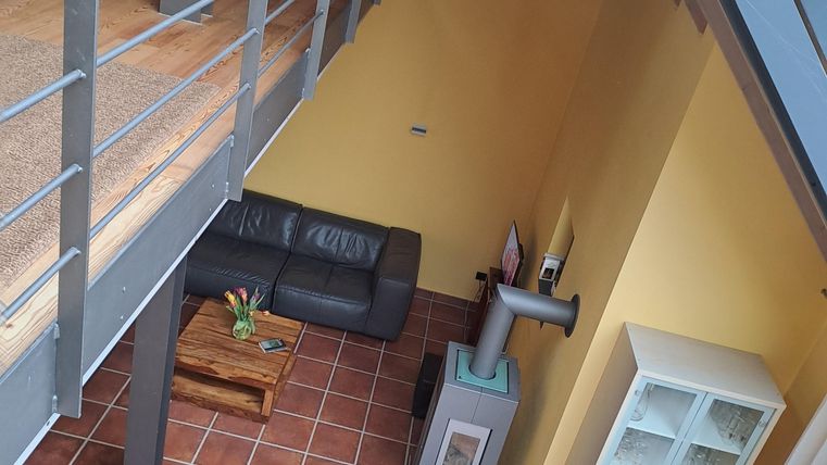 Ein modernes Wohnzimmer mit einem schwarzen Sofa und einem Holztisch. Die Wände sind in Gelb gestrichen, und es gibt einen Kamin sowie einen weißen Schrank.