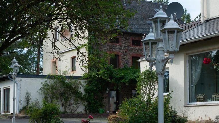 Eine Ansicht von einem ruhigen Wohngebiet mit historischen Gebäuden und modernen Laternen. Die Umgebung ist grün und einladend, mit Pflanzen und Bäumen.