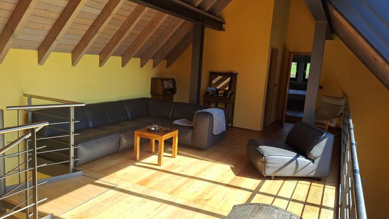 Ein heller Wohnraum mit Holzfußboden und gelben Wänden. Eine gemütliche Couch und ein Tisch bieten Platz zum Entspannen.
