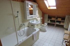 Ein großzügiges Badezimmer mit Badewanne und Waschbecken. Die Holzdecke und das Tageslicht schaffen eine helle, einladende Atmosphäre.
