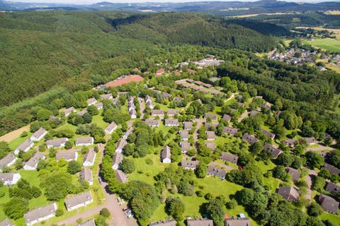 Eine grüne Wohnsiedlung umgeben von Bäumen und Wäldern. Die Häuser sind harmonisch in die Landschaft integriert.