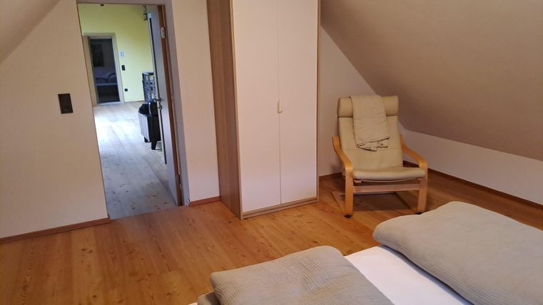 Ein gemütliches Schlafzimmer mit Holzfußboden. Im Hintergrund steht ein Schrank und ein Stuhl.