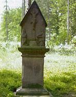 Ein steinernes Denkmal steht in einer grünen Wiese. Umgeben von Bäumen vermittelt es eine ruhige Atmosphäre.