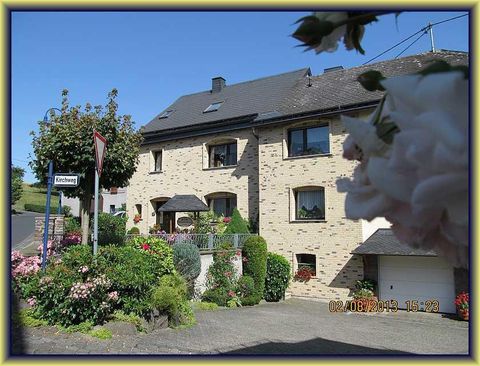 Ein schönes, zweistöckiges Haus mit Blumen und Pflanzen. Es gibt eine Straßenbeschilderung und einen gepflegten Vorgarten.